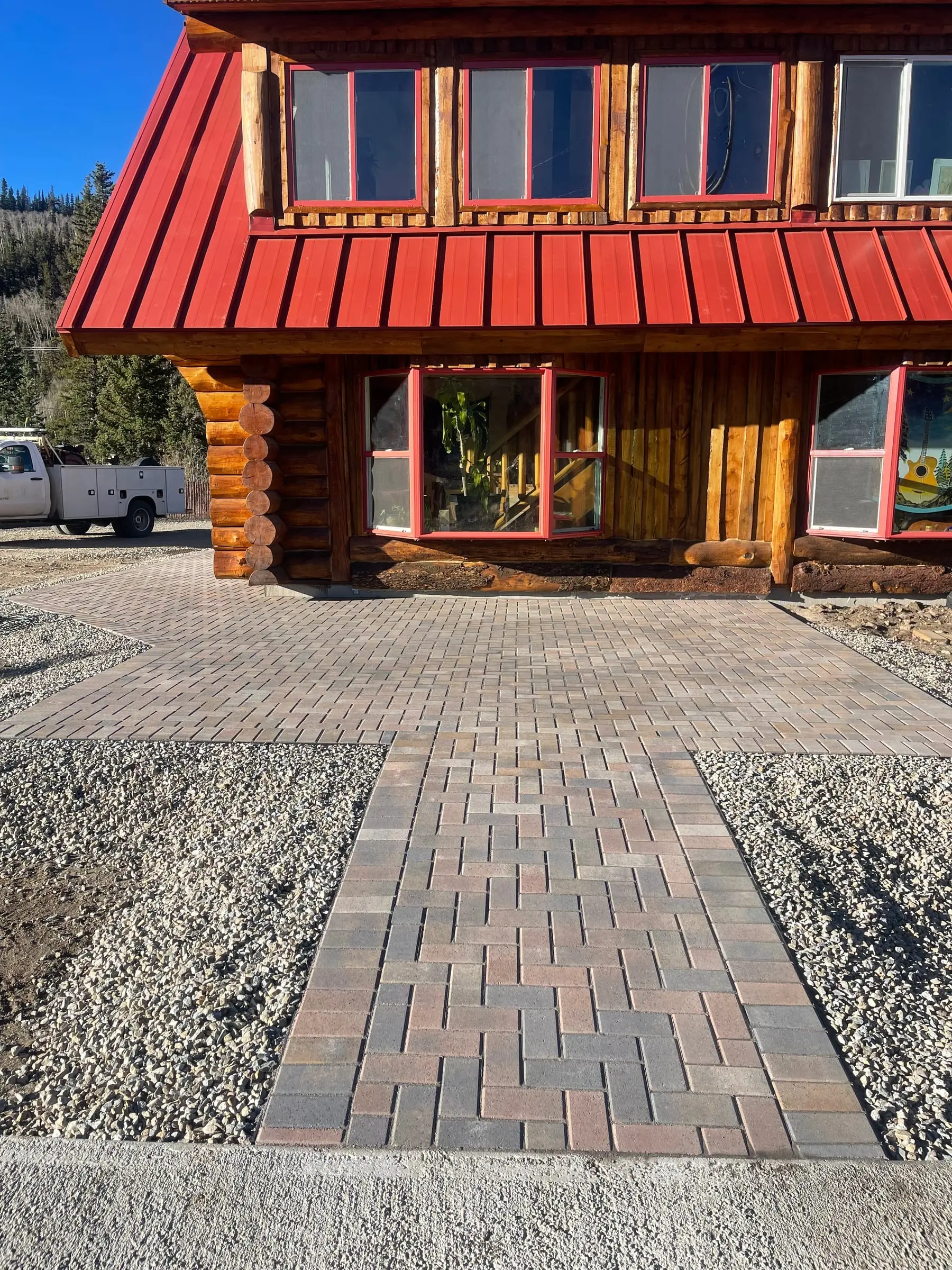 Brick paver driveway and entry apron at a red-roofed Breckenridge log home