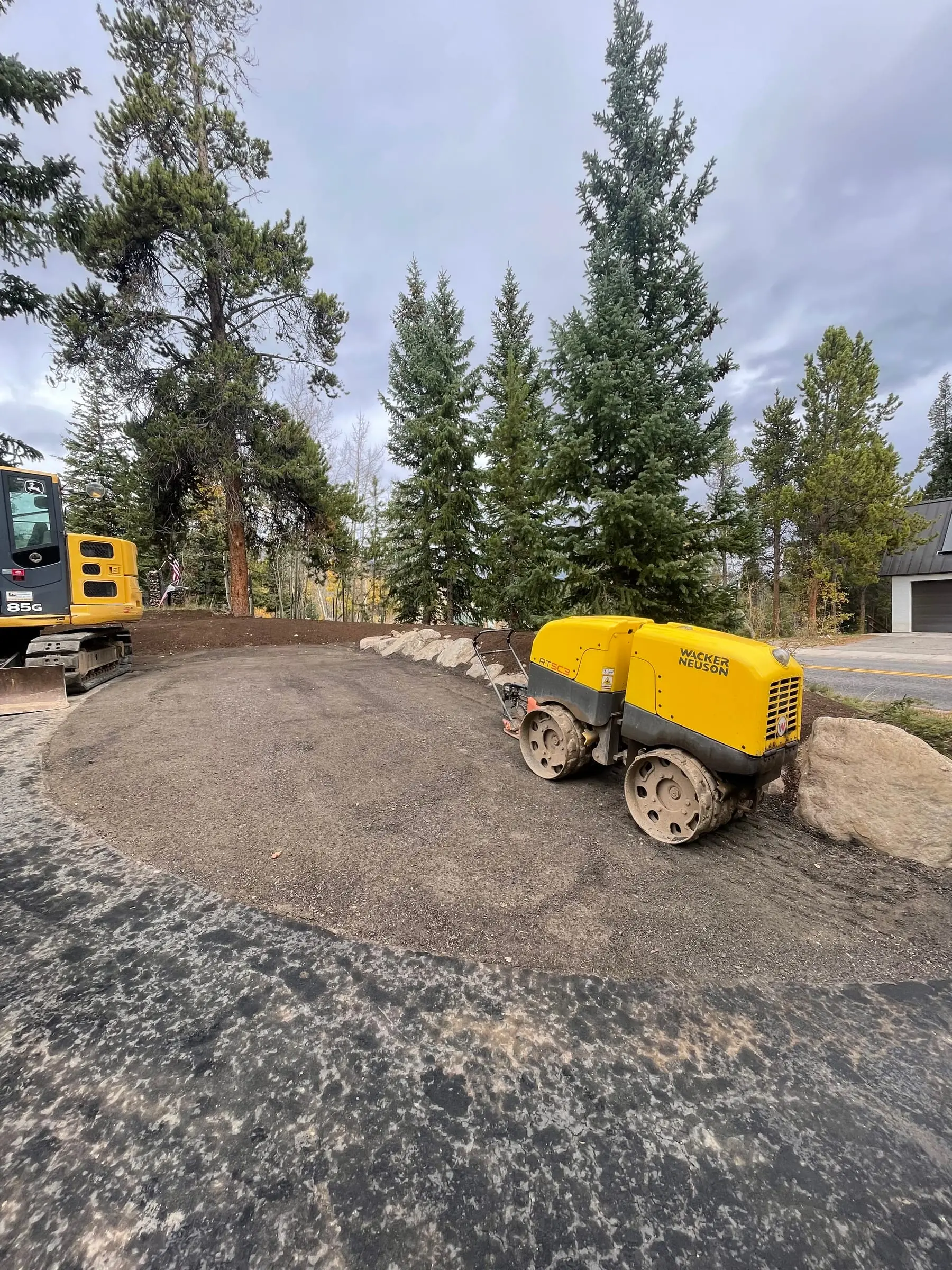 Compact track loader grading a gravel building pad on a Summit County jobsite