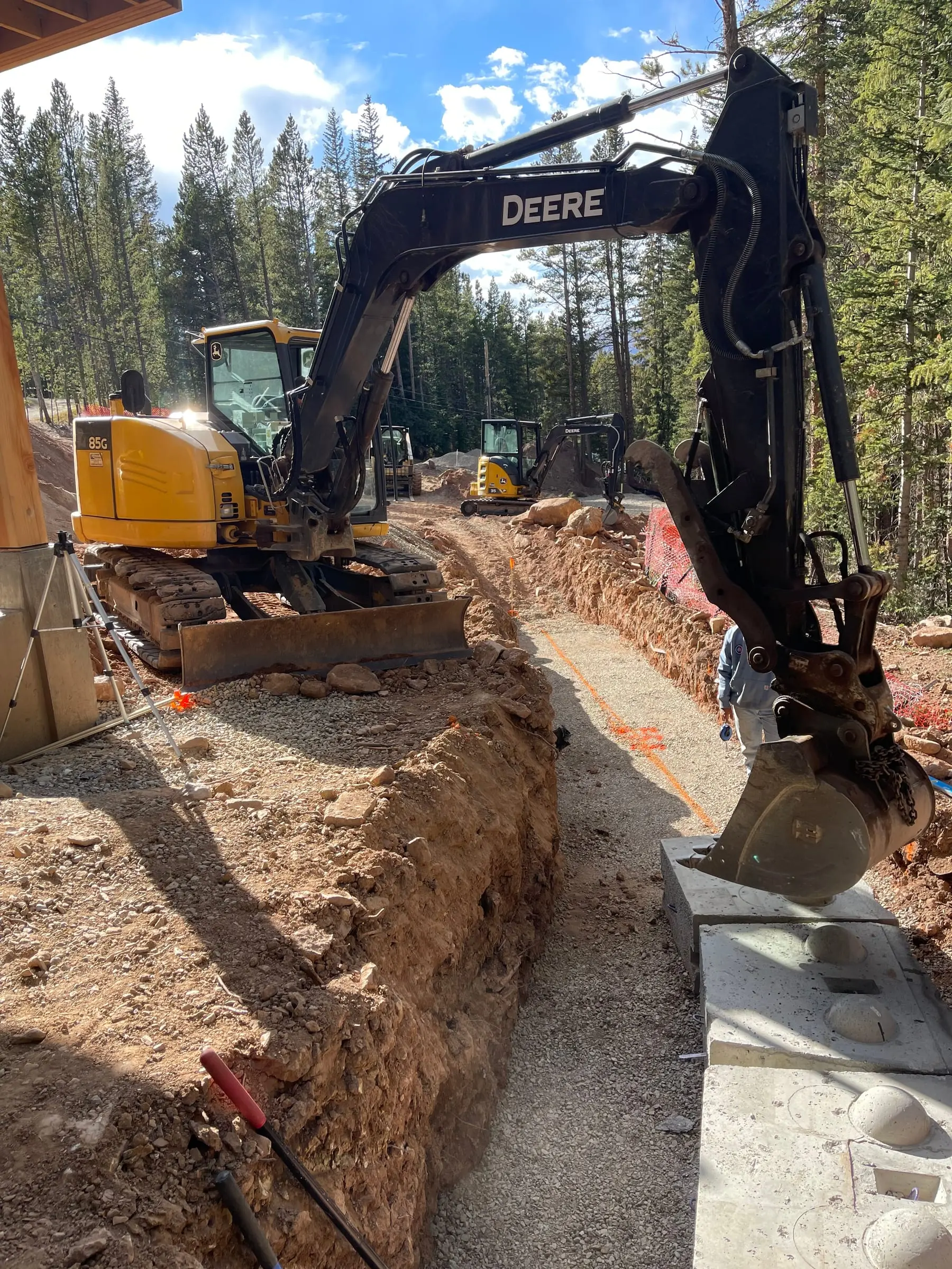 Excavator opening a utility trench across a mountain property